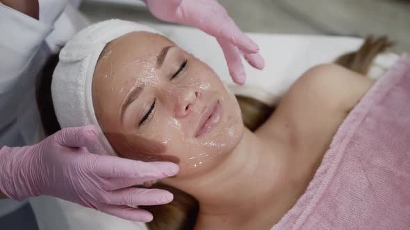 Beautician's Hands Applying Gel Before Rejuvenation Procedure in Cosmetic Clinic