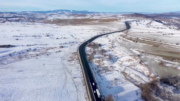Aerial View of a Winding Road With Passing Cars in a Frosty Winter Sunny Day