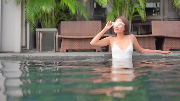 Young asian woman enjoy around outdoor swimming pool for leisure