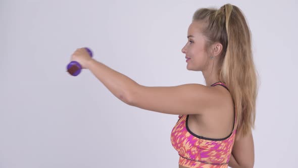 Profile View of Happy Young Blonde Woman Exercising with Dumbbells