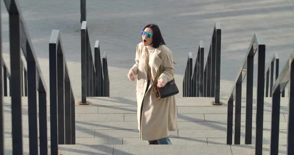 Energetic Dance of Joyful Caucasian Woman in Sunglasses and Beige Coat