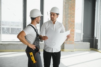 Construction concept of Engineer and Architect working at Construction Site with blue print.