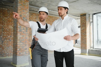 Construction concept of Engineer and Architect working at Construction Site with blue print.