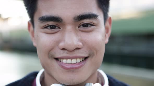 Closeup Portrait of Handsome Young Asian Man with Headphones Smiling at Camera