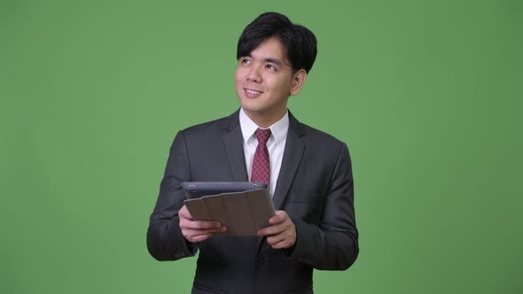 Young Handsome Asian Businessman Using Digital Tablet