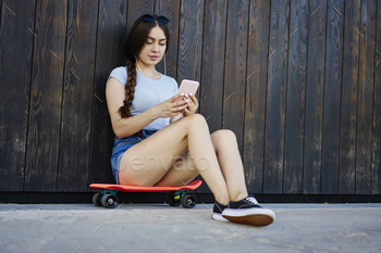 millennial hipster girl resting on penny board and chatting