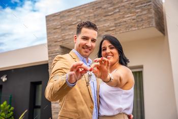 Smiling couple buying a new house showing the keys