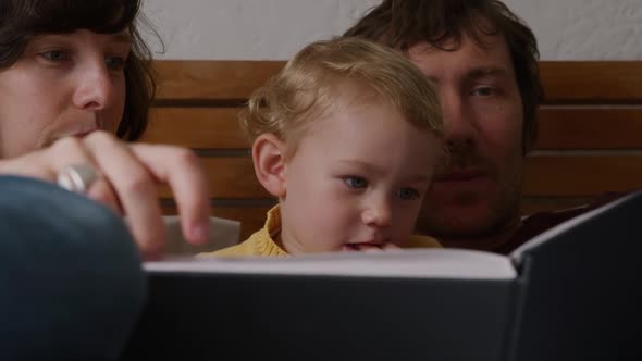 Front view of couple reading book to baby at home