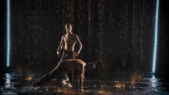 Performance By Two Acrobats in the Rain. Men Do Handstands and Balance in Slow Motion.