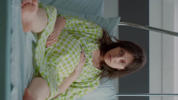 Vertical Video Portrait of Pregnant Person Sitting in Hospital Ward Bed
