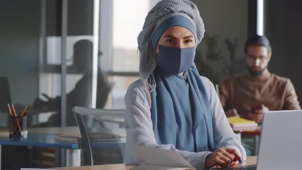 Businesswoman in Hijab and Mask Posing for Camera at Work
