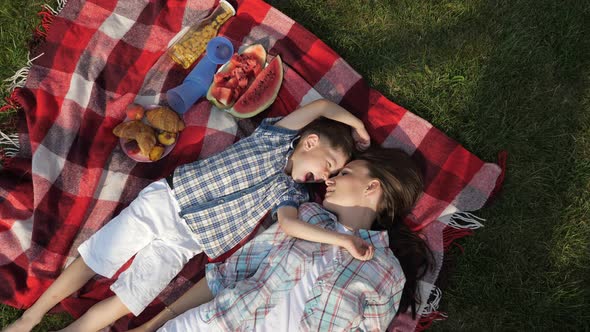 Mother and Happy Little Son Speak and Laugh Lying on Grass