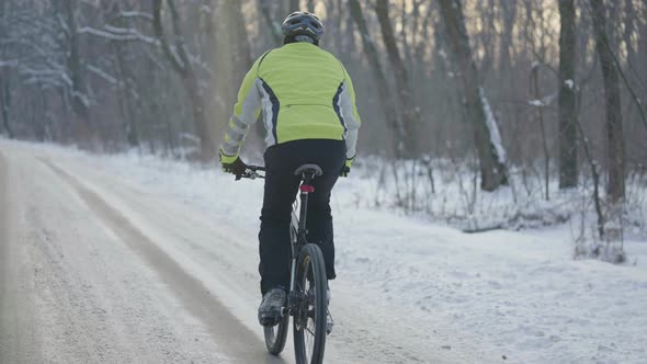 Rear View of a Man in a Helmet Riding a Sports Bike on a Snowcovered Slippery Road