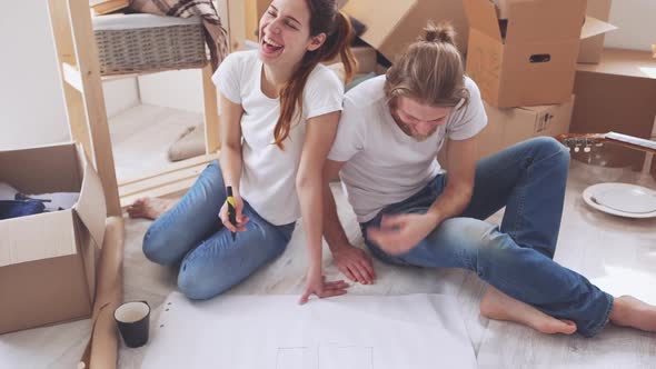 Young Caucasian Pair Planning Furnishings in Their New Flat in Slowmotion