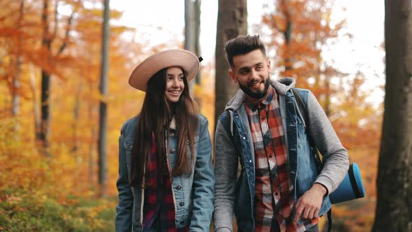 A Young Woman and a Man are Walking Through the Autumn Forest