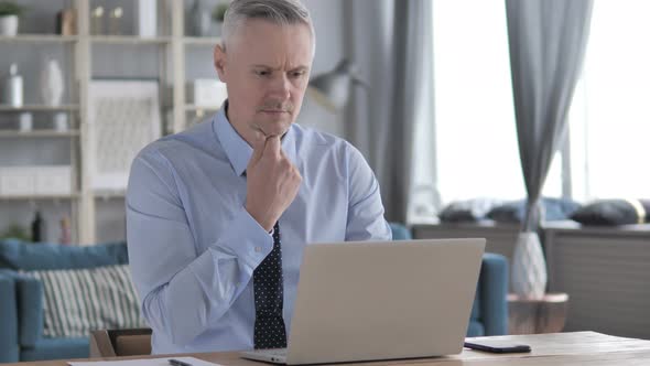 Pensive Gray Hair Businessman Thinking and Working on Laptop