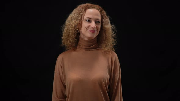 Medium Shot of Confident Smiling Woman Standing at Black Background Looking Around in Camera Flashes
