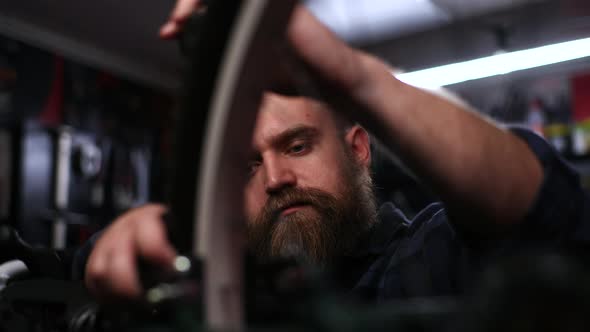 Closeup Face of Skilled Bicycle Repairman Tightening Screw on Frame of Bicycle with Screwdriver Near