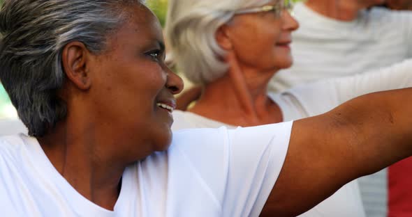 Senior friends doing stretching exercise in garden 4k