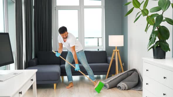 Man Cleaning the House and Having Fun with a Broom