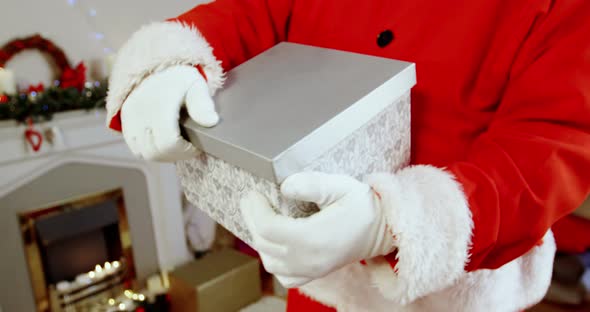 Mid section of santa claus holding gift box