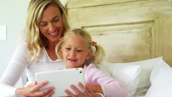 Mother and daughter using digital tablet in bedroom at home 4k