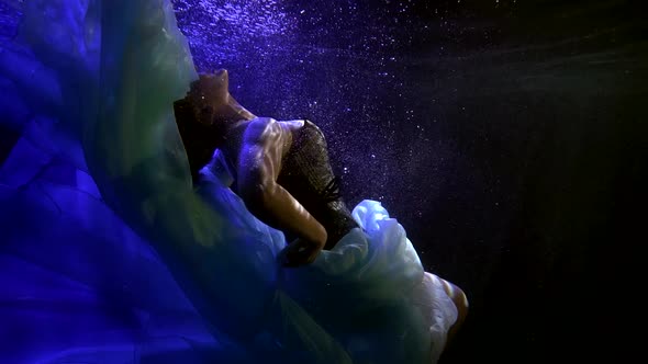 Romantic Woman Is Swimming in Dark Deepness in Pool, Splashing and Playing with White Fabric