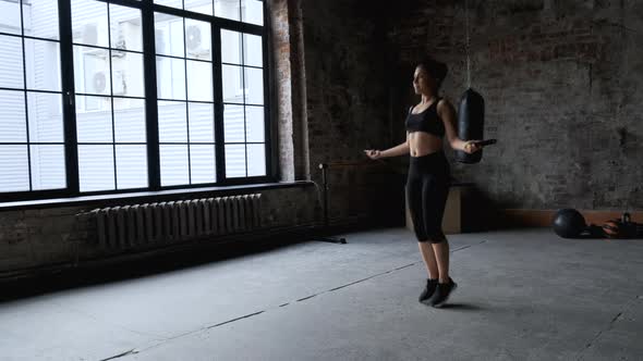 Young indian woman skipping rope in dark gym, Athletic Girl Dressed in Sportswear Black Top