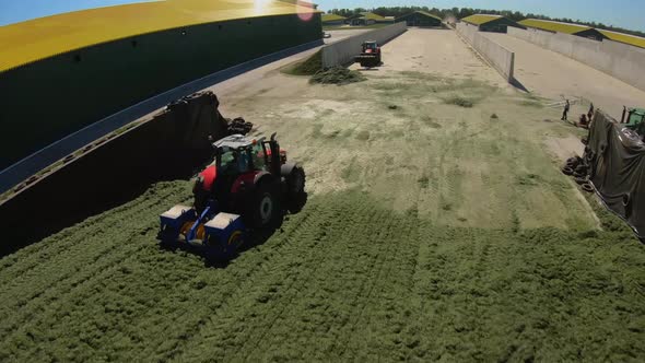 Copter flying around tractors in a silo on a farm