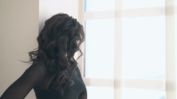 Lady with Hairstyle and Makeup Poses Near Large Window