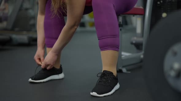 Unrecognizable Plussize Motivated Sportswoman Tying Shoelaces on Sneakers Standing Up Walking Away