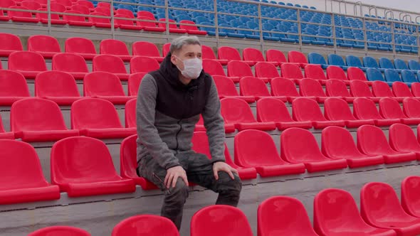 Young Man in Medical Mask Sitting on Stadium Bleachers Alone