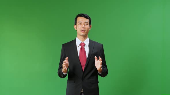 Asian Businessman In Suit Jacket Standing And Presenting Something On Green Screen Background