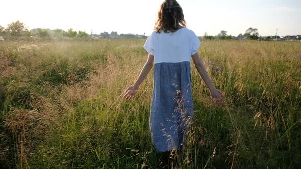 Woman Walks Across the Field and Hand Touches High Grass at Sunset, Slow Motion