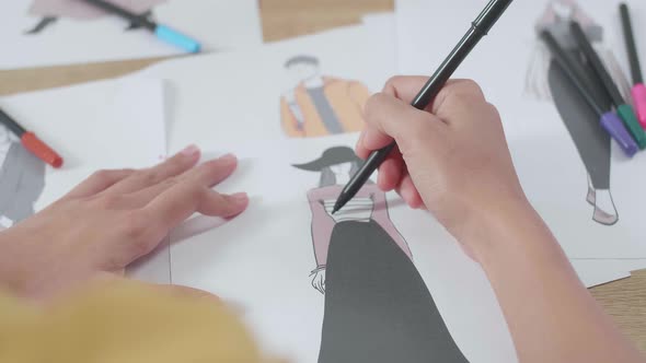 Close Up Of Female's Hand Designing Clothes On The Paper In The Studio