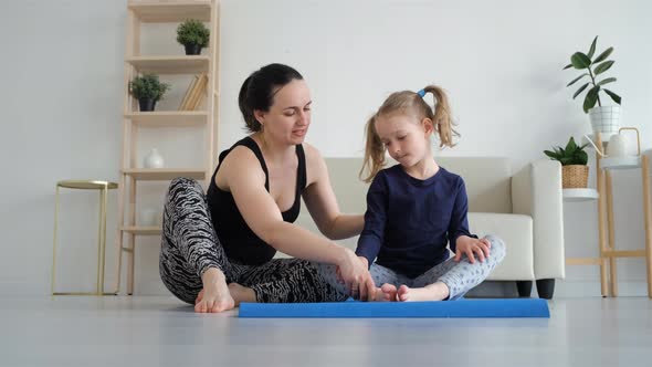 Woman Training on a Mat with Little Daughter