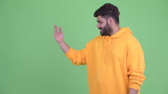 Happy Young Overweight Bearded Indian Man Talking While Showing Something