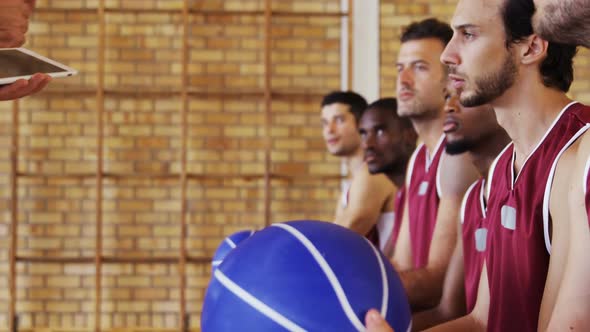 Basketball coach assisting players on digital tablet