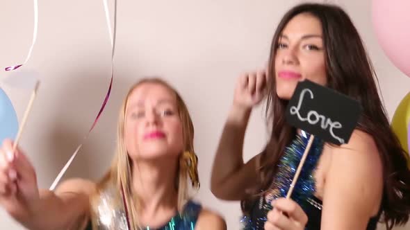 Sexy girls dancing with a sign in love in party photo booth