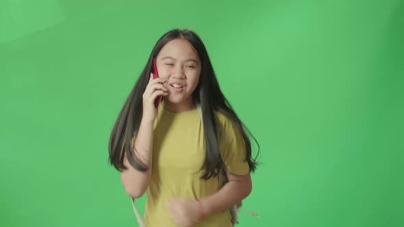 Asian Girl Student Talking On Mobile Phone And Running To School On Green Screen Chroma Key