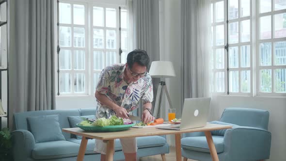 Smiling Asian Man Learn To Cooking Healthy Food Online With A Laptop At Home