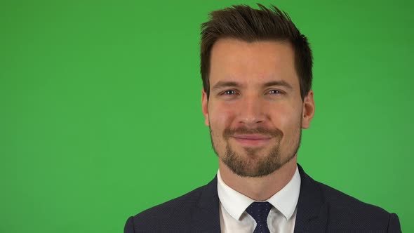 A Young Handsome Businessman Smiles at the Camera - Closeup - Green Screen Studio