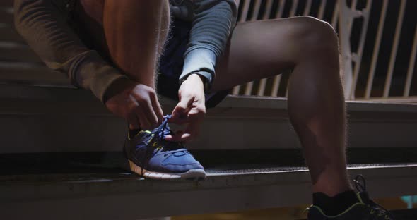 Caucasian male wearing a headlamp and tying his lacet on stairs in the evening