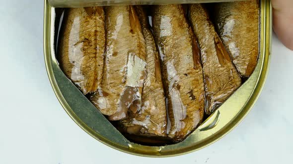 Hand Opens Metallic Tin Can of Canned Sprats in Oil