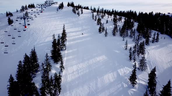 Panoramic top view from drone on cable way in ski resort. Ski lift elevator transporting skiers and