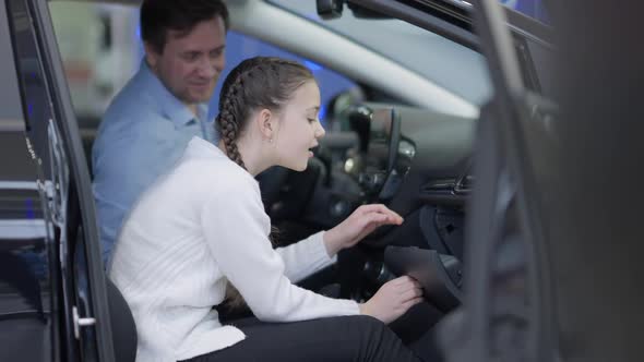 Side View of Girl Opening Glove Compartment and Taking Candy with Blurred Man Talking at Background