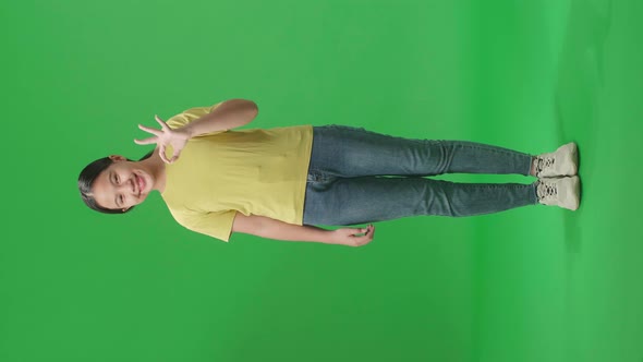 Full Body Of A Happy Young Asian Kid Girl Showing Okay Gesture To The Camera In The Green Screen