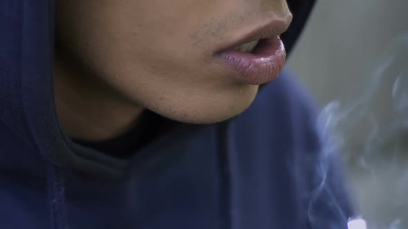 Young Man Smoking Cigarette, Nicotine Addiction, Risk of Lung Cancer, Closeup