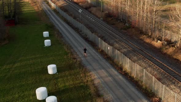 Man Running Down Countryside Dirt Road Next To Railroad Near Ostersund, Sweden. 4K Drone.