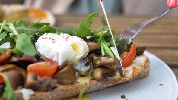 Woman Cuts Canape with Pouched Egg with Knife and Fork